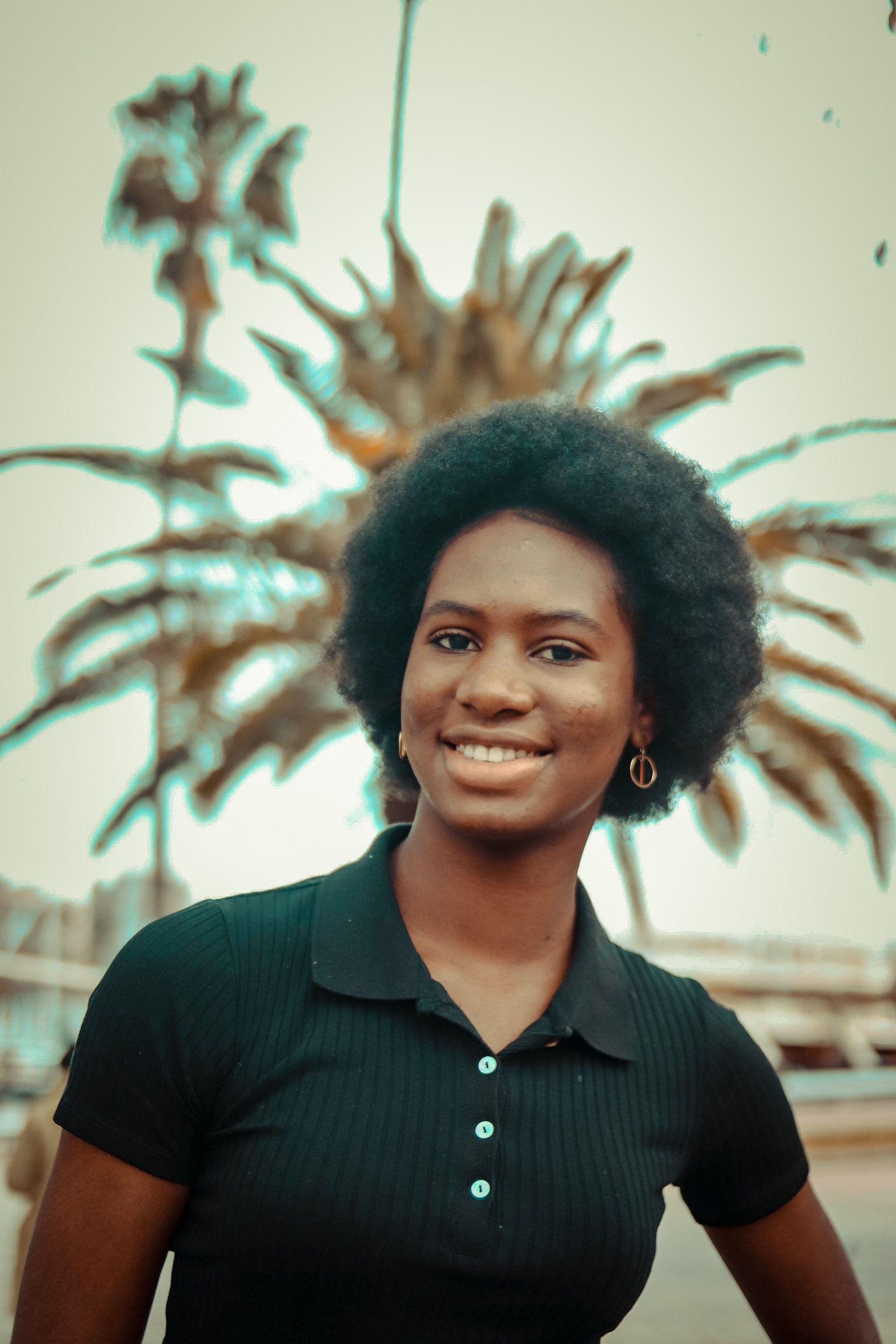 A cheerful woman smiling outdoors among palm trees